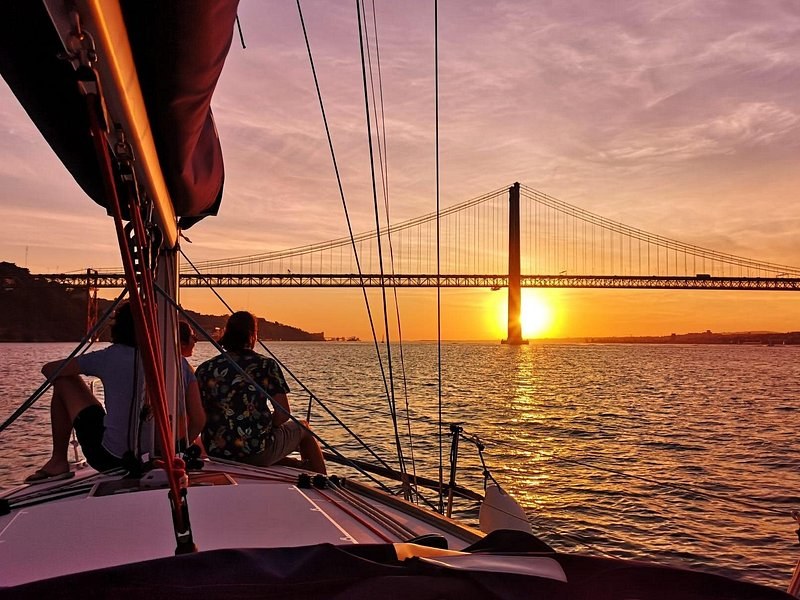 A sailboat's rigging framing the bridge at dusk