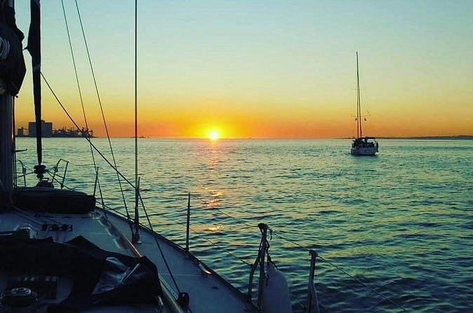 The sun setting over the estuary mouth, seen from a sailboat's bow