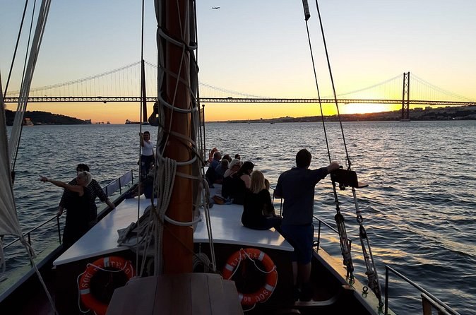Passengers on a traditional boat's deck heading towards the bridge